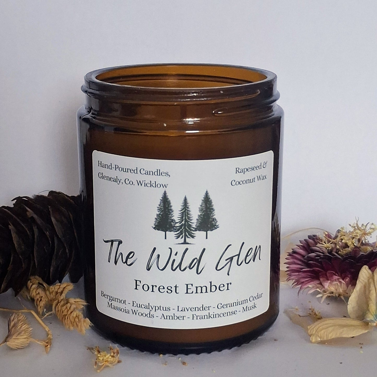 Brown candle jar labeled 'The Wild Glen Forest Ember' with decorative elements on a light background
